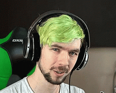 A Man With Green Hair Is Wearing Headphones And Looking At The Camera . GIF