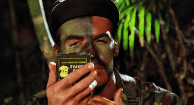 A Man With Half His Face Painted In Camouflage Holds A Box That Says Jimpac GIF