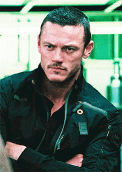 A Man With His Arms Crossed Looks At The Camera GIF