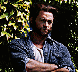 A Man With His Arms Crossed Stands In Front Of A Bush GIF