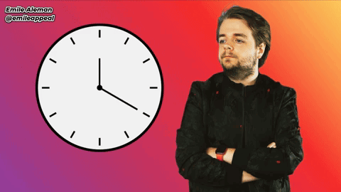 A Man With His Arms Crossed Stands In Front Of A Clock With Emilio Aleman Written On The Bottom Right GIF