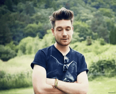 A Man With His Arms Crossed Wearing A Black Shirt With A Cat On It . GIF