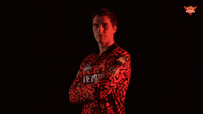 A Man With His Arms Crossed Wears A Red Shirt That Says Jio On It GIF
