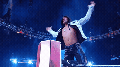 A Man With His Arms In The Air Stands On A Podium GIF