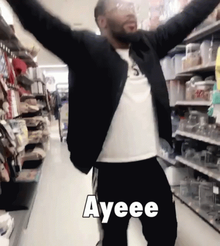 A Man With His Arms Outstretched In A Store With Ayeee Written In White Letters GIF