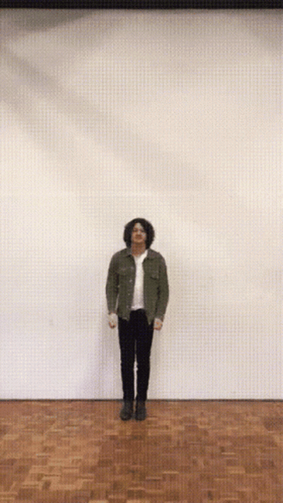 A Man With His Arms Outstretched Is Standing On A Wood Floor GIF