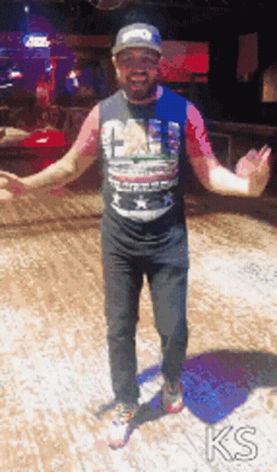 A Man With His Arms Outstretched Is Wearing A T-Shirt That Says ' Ks ' On It GIF