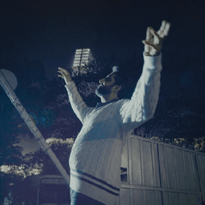A Man With His Arms Outstretched Is Wearing A White Sweater With Blue Stripes GIF
