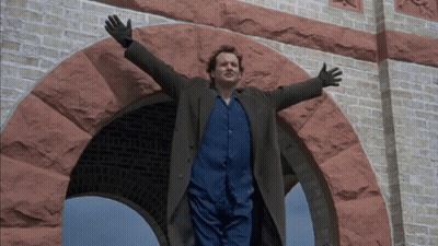 A Man With His Arms Outstretched Standing In Front Of A Brick Archway GIF