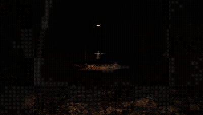 A Man With His Arms Outstretched Stands In The Dark GIF
