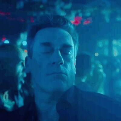 A Man With His Eyes Closed In A Dark Room With Blue Lights Behind Him GIF