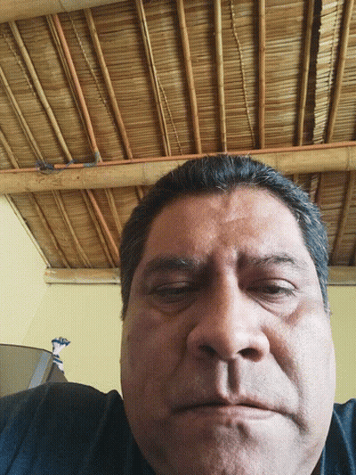 A Man With His Eyes Closed In Front Of A Straw Roof GIF