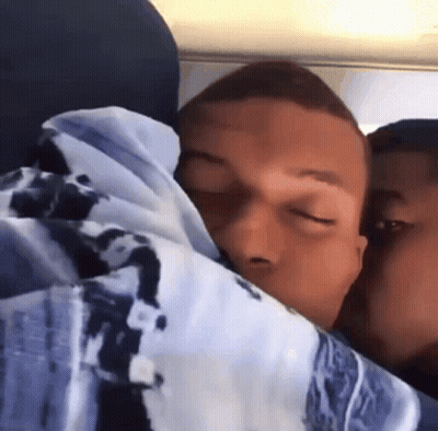 A Man With His Eyes Closed Is Hugging Another Man In A Blanket GIF