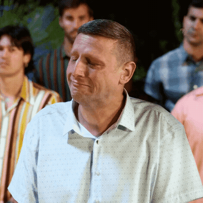 A Man With His Eyes Closed Is Standing In A Crowd Of Men GIF