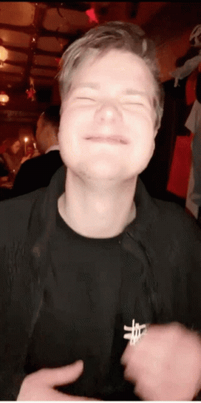 A Man With His Eyes Closed Is Wearing A Black Shirt With A Cross On The Chest GIF