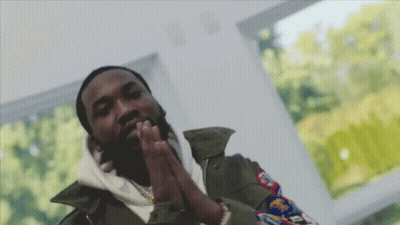 A Man With His Hands Folded In Front Of A Window With Trees Behind Him GIF