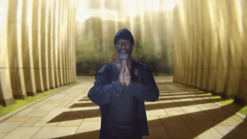 A Man With His Hands Folded In Front Of Columns GIF