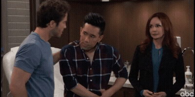 A Man With His Hands On His Stomach Is Talking To A Woman And A Man In A Blue Shirt GIF
