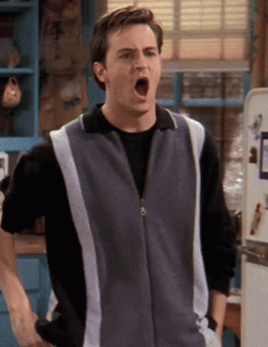 A Man With His Mouth Open Is Wearing A Grey And White Vest GIF