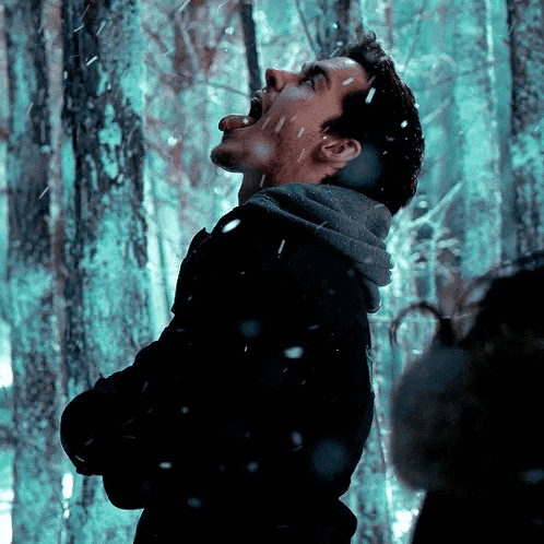 A Man With His Tongue Out Is Standing In A Snowy Forest GIF