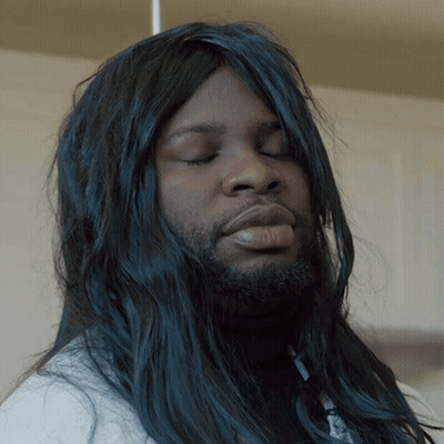 A Man With Long Black Hair And A Beard Looks Down With His Eyes Closed GIF