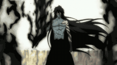 A Man With Long Black Hair And A Mask On His Face Is Standing In A Dark Room . GIF
