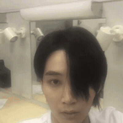 A Man With Long Black Hair Is Taking A Selfie In Front Of A Mirror GIF