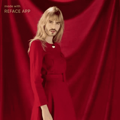 A Man With Long Blonde Hair And A Beard Is Wearing A Red Dress GIF