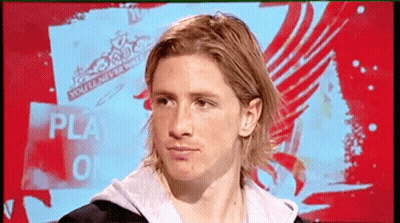 A Man With Long Blonde Hair Is Sitting In Front Of A Sign That Says Play GIF