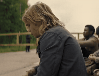 A Man With Long Blonde Hair Is Sitting On A Bench GIF