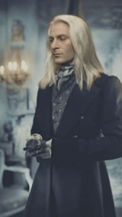 A Man With Long Blonde Hair Is Standing In A Room GIF