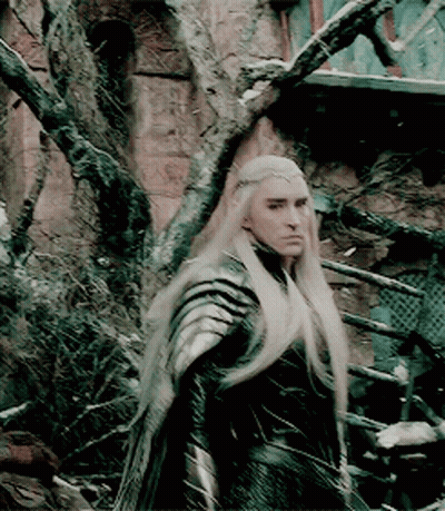 A Man With Long Blonde Hair Is Standing In Front Of A Tree GIF