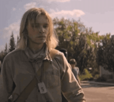 A Man With Long Blonde Hair Is Wearing A Lanyard Around His Neck With The Letter D On It GIF