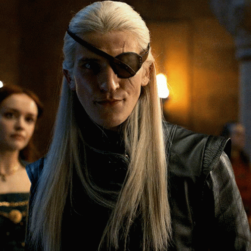 A Man With Long Blonde Hair Wearing A Black Leather Jacket And An Eye Patch GIF