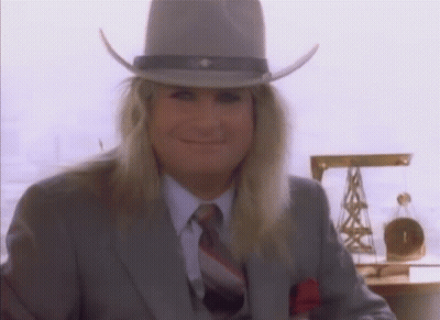 A Man With Long Blonde Hair Wearing A Cowboy Hat And Suit GIF