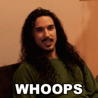 A Man With Long Curly Hair And A Mustache Is Wearing A Green Shirt That Says " Whoops " GIF