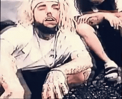 A Man With Long Dreadlocks And A Beard Is Sitting On The Ground With His Eyes Closed . GIF