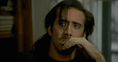 A Man With Long Hair And A Beard Has His Hand On His Face GIF