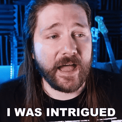 A Man With Long Hair And A Beard Has The Words I Was Intrigued Above His Head GIF