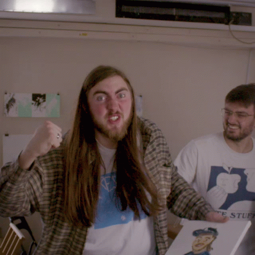 A Man With Long Hair And A Beard Is Holding A Book That Says ' Ts Stuff ' GIF