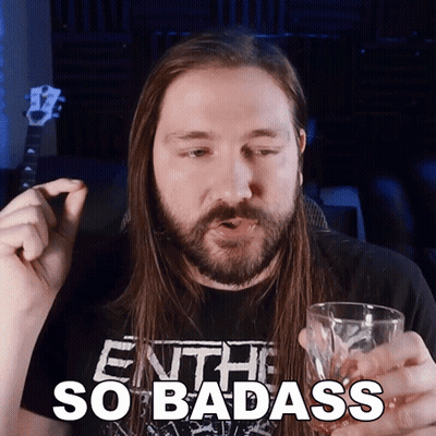A Man With Long Hair And A Beard Is Holding A Glass With The Words So Badass Written On It GIF