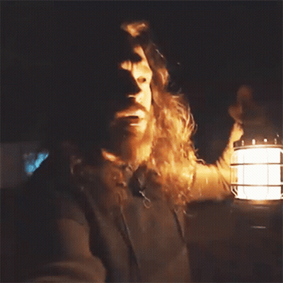 A Man With Long Hair And A Beard Is Holding A Lantern In His Hand GIF