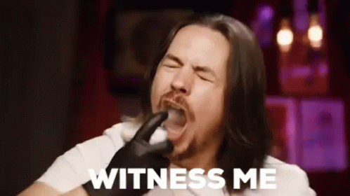 A Man With Long Hair And A Beard Is Holding A Pipe In His Mouth And Saying `` Witness Me '' . GIF