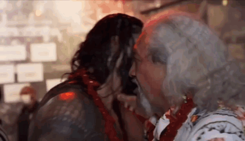 A Man With Long Hair And A Beard Is Kissing A Woman . GIF
