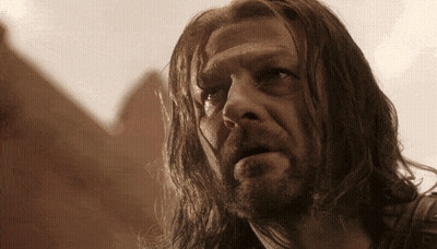 A Man With Long Hair And A Beard Is Looking At Something GIF