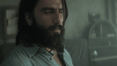 A Man With Long Hair And A Beard Is Looking Down GIF