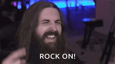 A Man With Long Hair And A Beard Is Making A Devil Horns Sign With His Hands . GIF