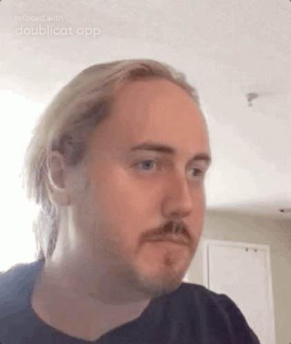 A Man With Long Hair And A Beard Is Making A Funny Face . GIF