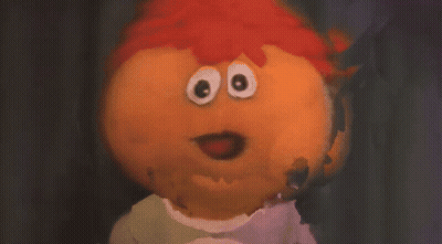 A Man With Long Hair And A Beard Is Making A Funny Face In Front Of A Purple Wall . GIF