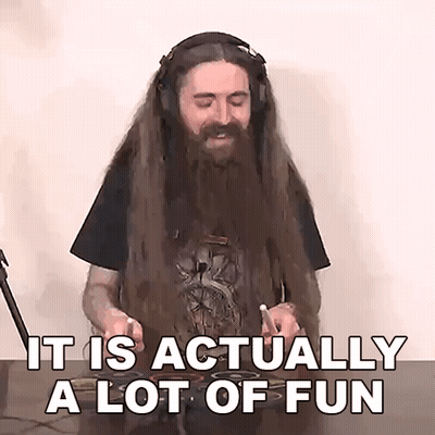 A Man With Long Hair And A Beard Is Playing Drums And Says " It Is Actually A Lot Of Fun " . GIF